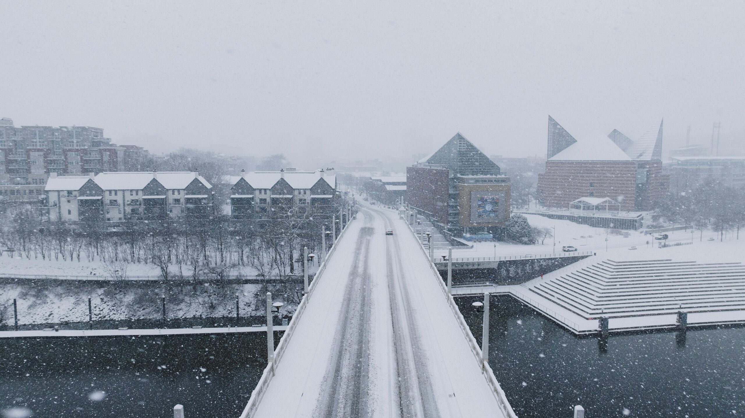 Luftaufnahme einer schneebedeckten Brücke, die an einem Wintertag zu modernen Gebäuden führt.