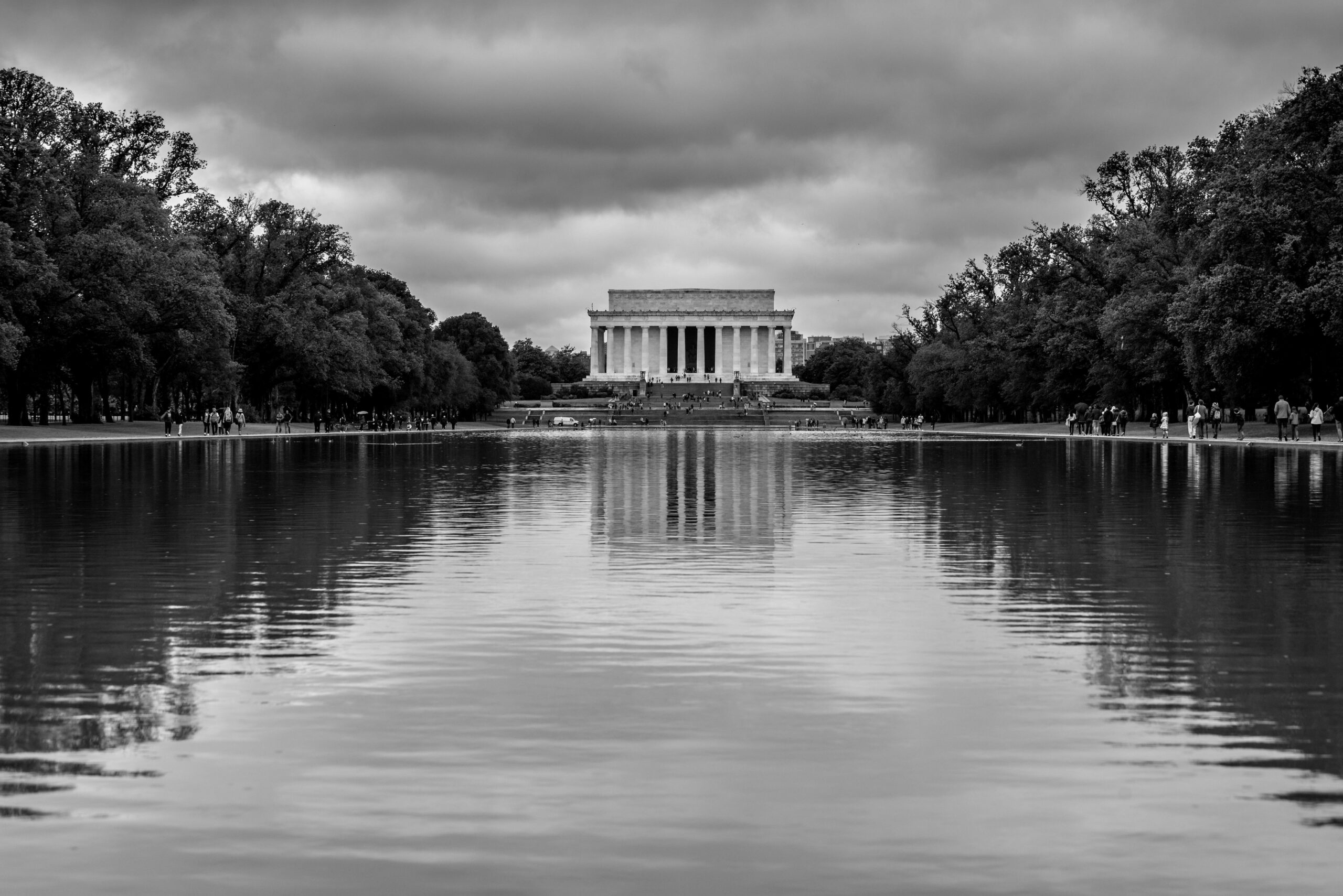 Schwarz-WeiÃŸ-Ansicht des Lincoln Memorial vom reflektierenden Pool unter bewÃ¶lktem Himmel.