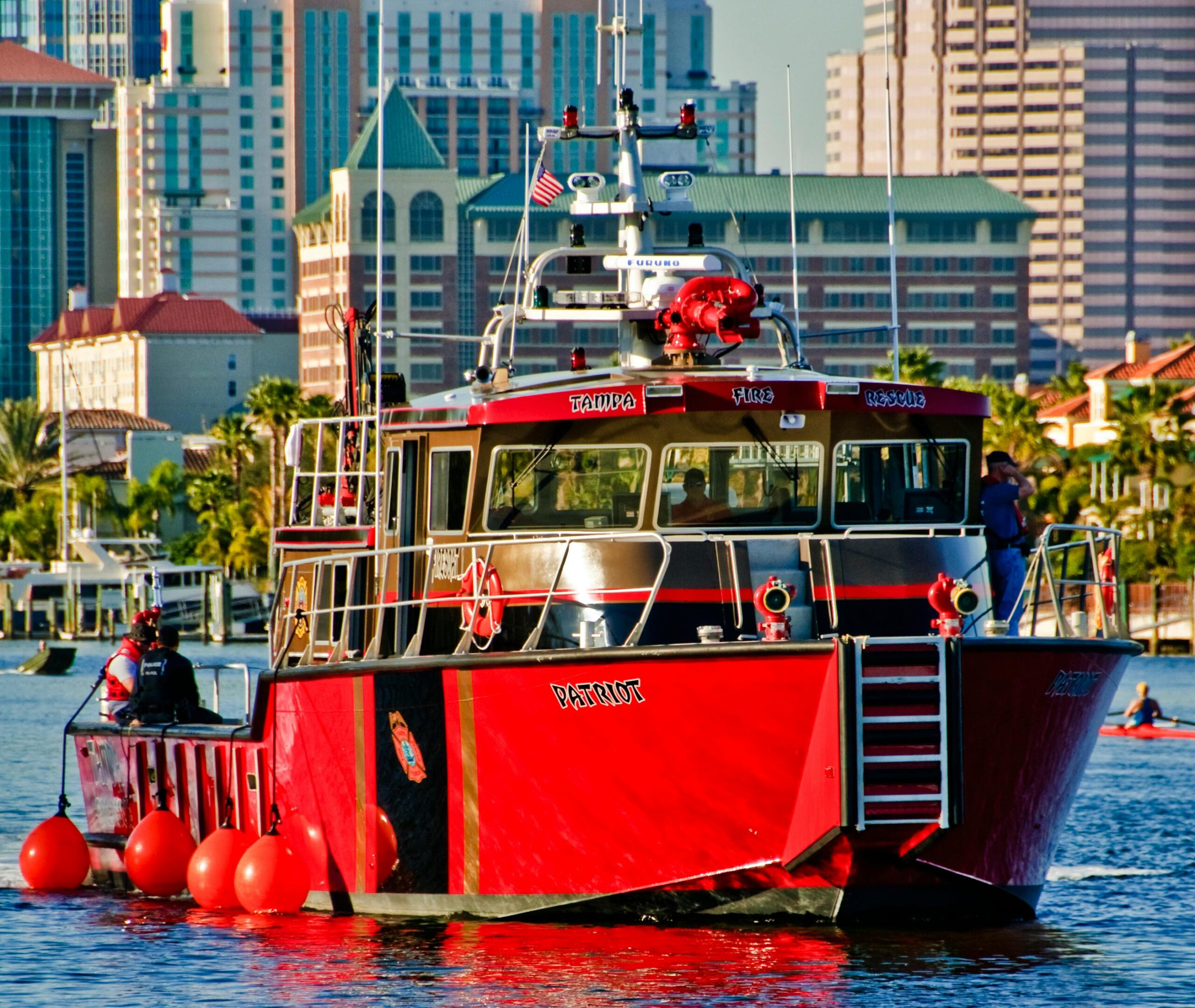 Leuchtend rotes Feuerwehrboot vor der Kulisse der Stadtlandschaft von Tampa, Florida.