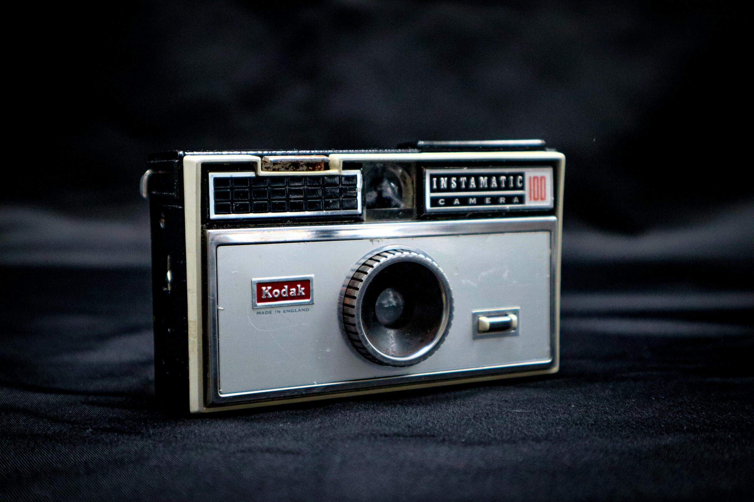 Nahaufnahme einer alten Kodak Instamatic 100-Kamera mit dunklem Hintergrund.