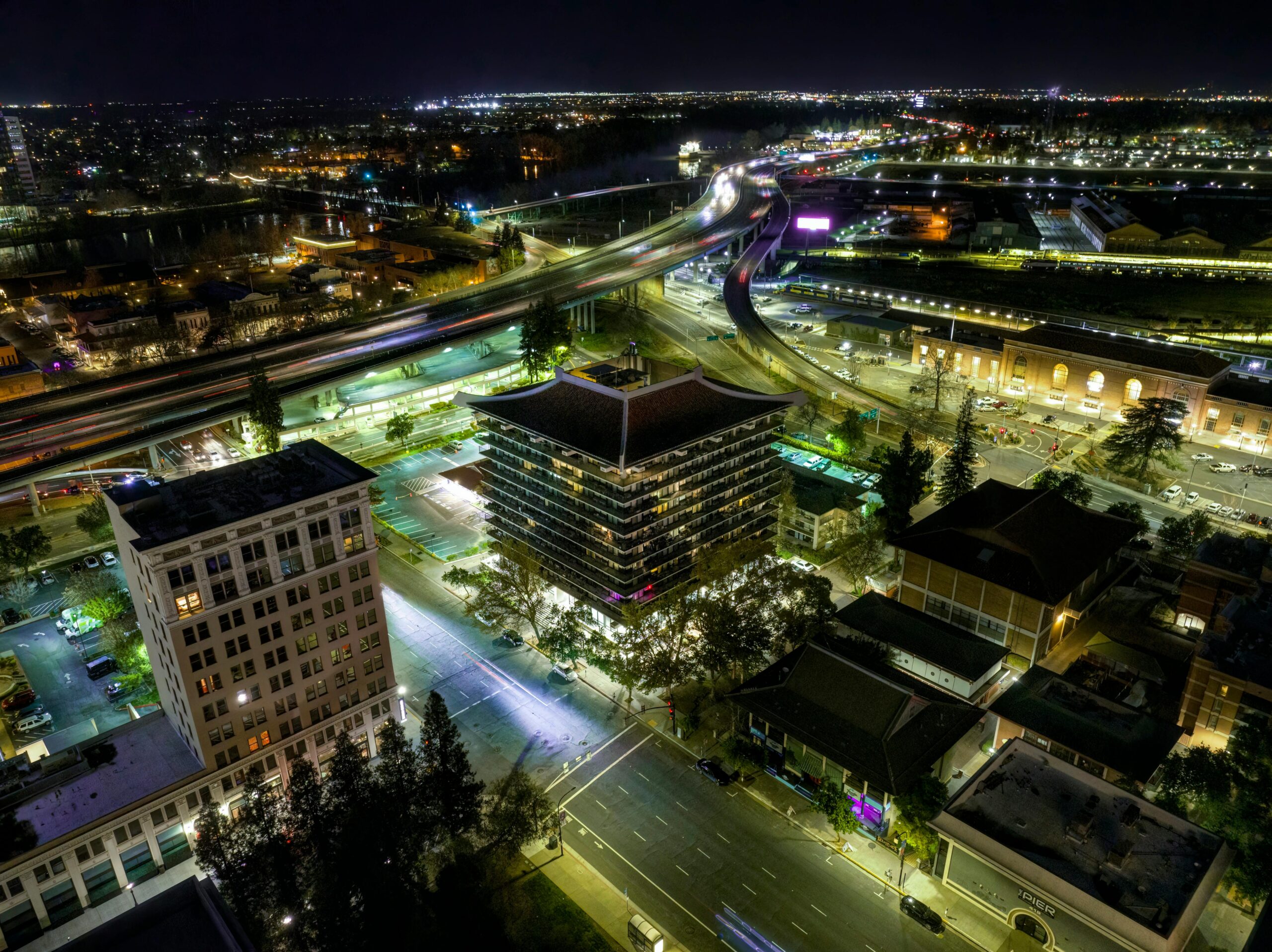 Eine atemberaubende Luftaufnahme der Innenstadt von Sacramento bei Nacht, die beleuchtete Geb&Atilde;&curren;ude und Autobahnen zeigt.