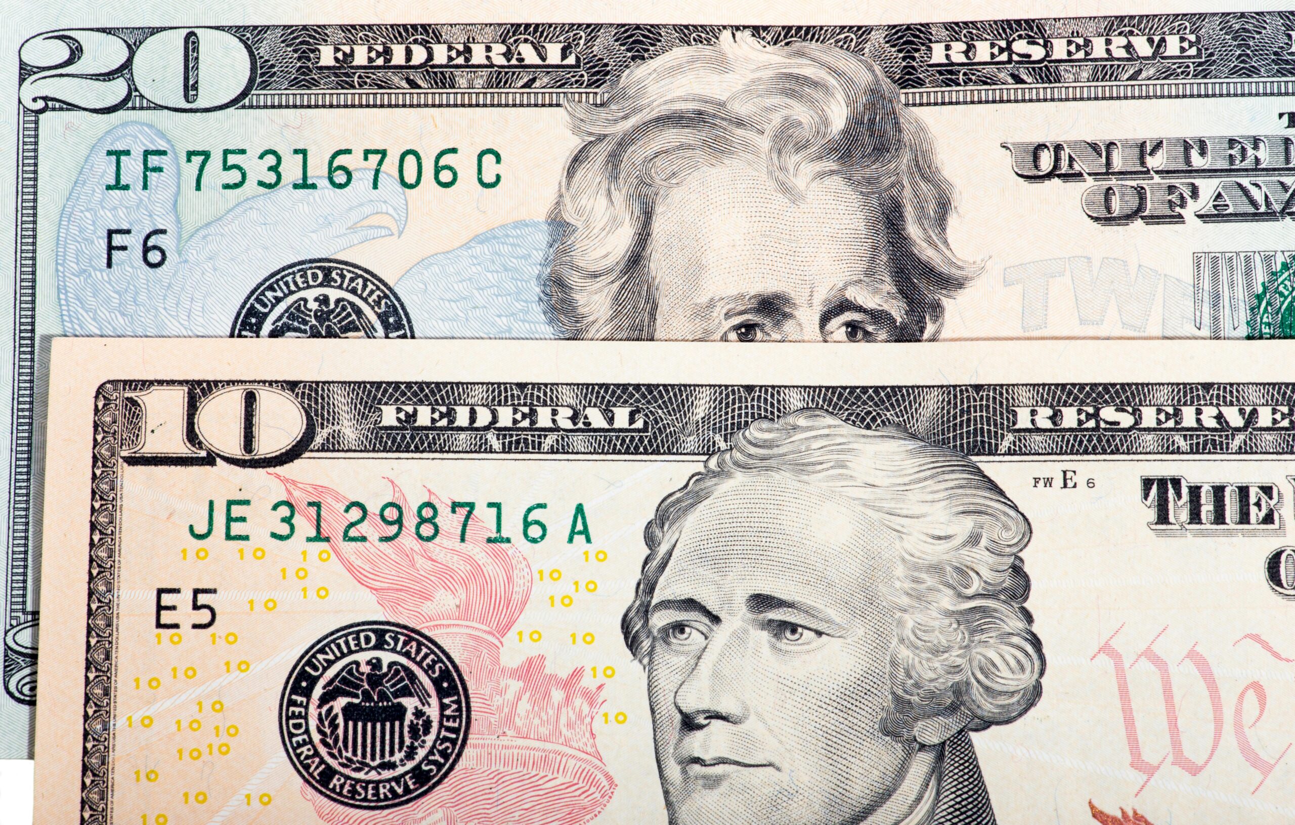 Detailansicht von US-amerikanischen Zehn- und Zwanzig-Dollar-Scheinen, wobei Design und Textur hervorgehoben werden.