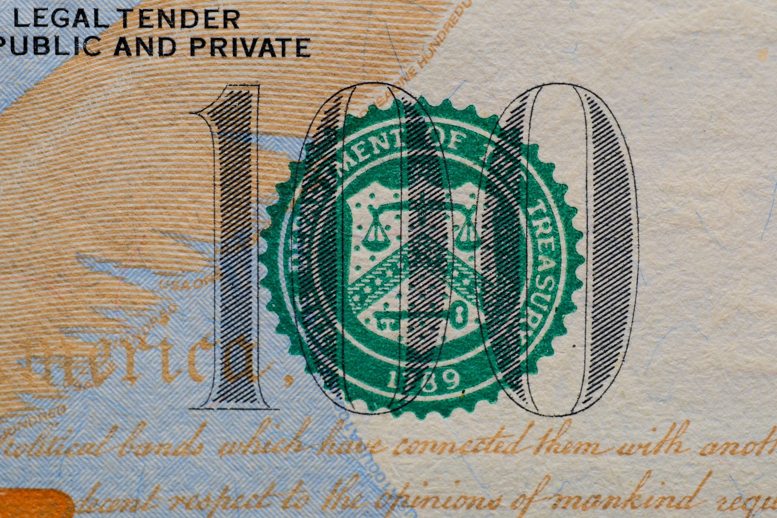 Detailansicht des 100-Dollar-Scheins der USA mit dem Siegel des Finanzministeriums und aufgedrucktem Text.